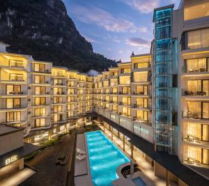a hotel with a swimming pool in front of a mountain at Guilin Yangshuo Shixi Landscape Hotel in Yangshuo