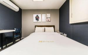 a bedroom with a large white bed and a chair at Donkey Hotel in Bucheon
