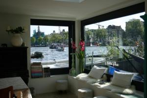 een kamer met een raam met uitzicht op een rivier bij Houseboat Ark van Amstel in Amsterdam