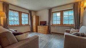 a living room with a couch and a tv and windows at Appartamento Montagnards in Morgex
