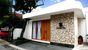 a small white house with a wooden door at Among Villa in Yogyakarta
