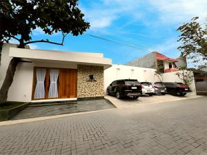 a house with cars parked in a parking lot at Among Villa in Yogyakarta