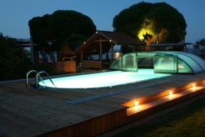 a swimming pool with lights on a deck at night at Apartamentai Roma in Neringa +9 photos