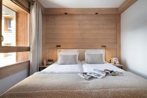 a bedroom with a bed with a wooden wall at MGM Hôtels & Résidences - Résidence Manaka in Aime-La Plagne