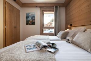 a bedroom with a bed with a book on it at MGM Hôtels & Résidences - Résidence Manaka in Aime-La Plagne