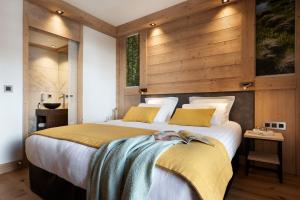 a bedroom with a large bed with a wooden wall at MGM Hôtels & Résidences - Résidence Manaka in Aime-La Plagne +53 photos