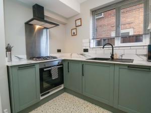 a kitchen with green cabinets and a sink at Steam and Stay Hoole in Chester