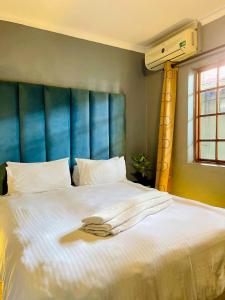 a bed with white sheets and a blue headboard at Palmetto guesthouse in Mahikeng +45 photos