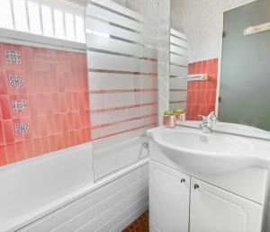 a bathroom with a white sink and pink tiles at Studio Cosy avec terrasse et parking privé in Cap d'Agde +22 photos