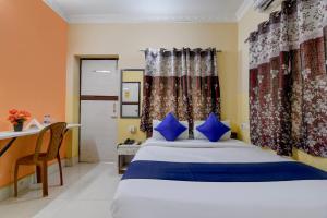 a bedroom with a bed with blue pillows and a desk at Avinaav Inn in New Town