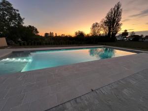 a swimming pool with a sunset in the background at Agriturismo Cà Nuova in Minerbio