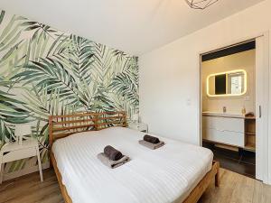 a bedroom with a white bed with a tropical wallpaper at Le Forum - Appartement rare - Parking privé - Centre - Reims in Reims