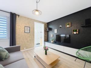 a living room with a couch and a tv at Le Forum - Appartement rare - Parking privé - Centre - Reims in Reims