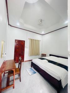 a bedroom with a bed and a wooden table at Nongkhiaw Chansai Guesthouse in Nongkhiaw