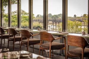 a restaurant with tables and chairs and windows at Muni Kyoto in Kyoto