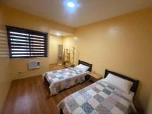 a bedroom with two beds and a window with a window at Apt101 Guest House in Bacoor