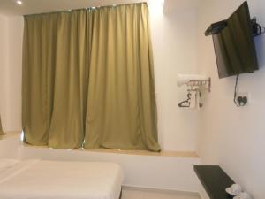 een kamer met een groen gordijn en een televisie bij F.M GUESTHOUSE in Kampong Darat Tanah Puteh