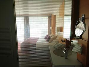a bathroom with a sink and a bedroom with a window at Le Churchill Hôtel & Spa in Carnac