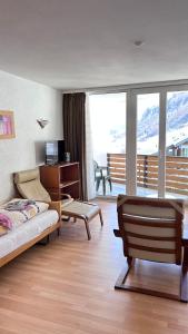 a bedroom with a bed and a desk and a balcony at Matterhof in Leukerbad