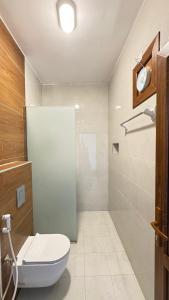 a bathroom with a white toilet and a shower at Al khitaym guest house in Sa‘ab Banī Khamīs