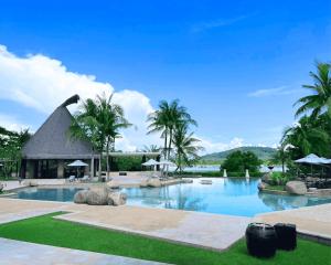 a swimming pool with palm trees and a building at BB Luxury Villa in Phuket