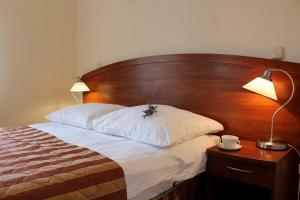 a bed with a wooden headboard and a table with a lamp at Pensjonat Perła Polanicy in Polanica-Zdrój