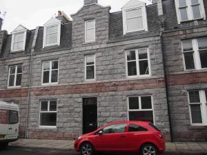 a red car parked in front of a brick building at APL Apartments in Aberdeen