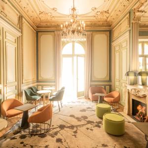 ein Zimmer mit Stühlen, Tischen und einem Kamin in der Unterkunft Hôtel Vendôme in Nizza
