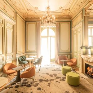ein Zimmer mit Stühlen, Tischen und einem Kronleuchter in der Unterkunft Hôtel Vendôme in Nizza