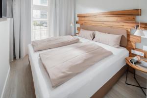 a bedroom with a large white bed with a wooden headboard at Nordstrandperlen Apartments in Norderney