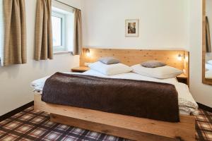 a bedroom with a wooden bed with two pillows at Haus Bergfrieden in Kaunertal