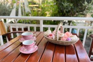 a basket of cookies and two cups on a wooden table at Villa Leonidas in Nea Vrasna