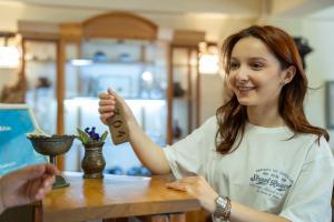 a woman sitting at a table holding a piece of wood at Hotel Mirhav in Goris