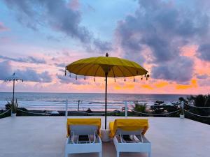 two chairs and an umbrella on the beach with the ocean at Trika Surfcamp Bali in Airsatang