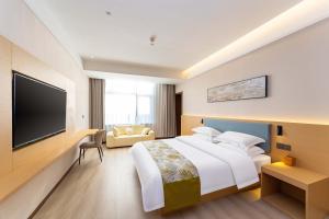 a hotel room with a bed and a flat screen tv at Shiershan · Yuntang Hotel in Qingdao
