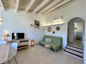 a living room with a green couch and a television at Apartamentos Islanders in Cala en Forcat