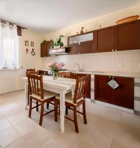 a kitchen with a white table and wooden chairs at Villa Colline Fiorite in Putignano