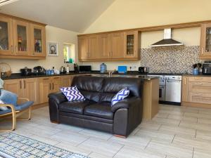 a living room with a leather couch in a kitchen at Awel Deg in Pembrokeshire +26 photos