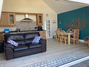a living room with a leather couch and a kitchen at Awel Deg in Pembrokeshire