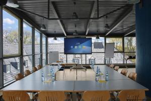 a conference room with a large table and a large screen at Jugendherberge Aachen - Membership required in Aachen