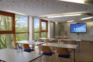 a classroom with tables and chairs and a projection screen at Jugendherberge Aachen - Membership required in Aachen +19 photos
