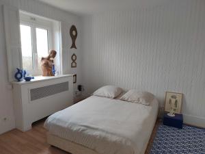 a white bedroom with a bed and a window at Le Flow de Ginette in La Celle-sous-Gouzon
