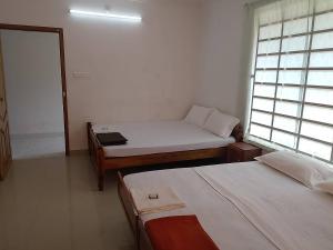 a room with two beds and a window at Somatheertham Resort in Kovalam