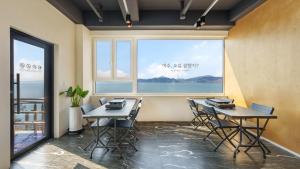 a room with two tables and chairs and a large window at Yeosu Jangsuri Poolvilla&Spa Pension in Yeosu