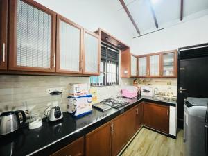 a kitchen with wooden cabinets and a black counter top at Sasanda Villa in Weligama