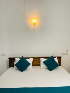 a bed with blue and white pillows on it at Sasanda Villa in Weligama