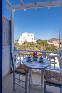 a table and chairs on a balcony with a view of the beach at Heliotropio Studios & Apartments in Pollonia