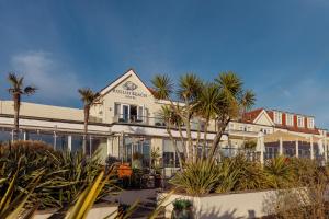 a large white building with palm trees in front of it at Roslin Beach Hotel in Southend-on-Sea