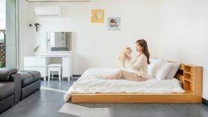 a woman sitting on a bed with a dog at Chuncheon Dogandstay in Chuncheon