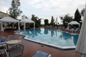 ein großer Swimmingpool mit Stühlen, Tischen und Sonnenschirmen in der Unterkunft SKG Assembly Β&Β Hotel in Thessaloniki